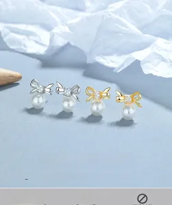Macro detail of 925 silver bow earrings with zircon center and dangling white pearl beads