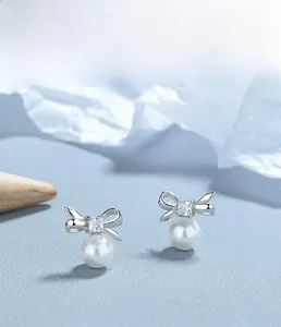 Macro view of S925 sterling silver bow earrings with zircon and pearl details