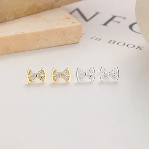 Macro detail of silver and gold bow earrings with sparkling cubic zirconia settings