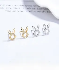 Détail macro de boucles d'oreilles lapin ajourées en or et argent avec zircons brillants