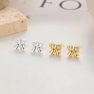 Close-up of elegant bow stud earrings with sparkling crystals in silver and gold finish