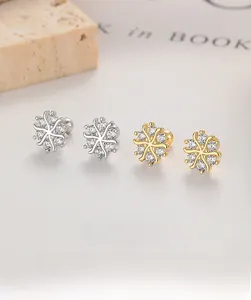 Close-up of snowflake stud earrings in gold and silver finish with zircon inlay