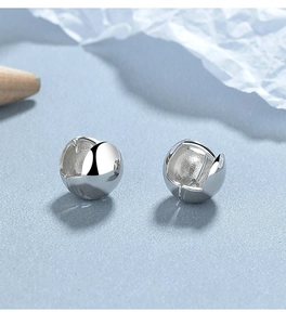 Détail macro de boucles d'oreilles huggie en argent sterling 925 poli sur fond bleu