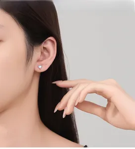 Close-up of model wearing heart-shaped moonstone stud earrings in 925 sterling silver