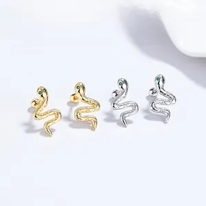 Close-up of snake stud earrings in silver and gold with green zircon eyes and scale texture