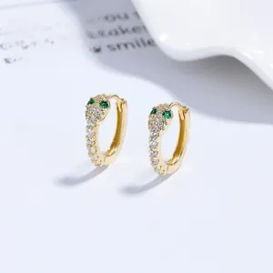 Close-up of golden snake hoop earrings with white zircons and green stone eyes