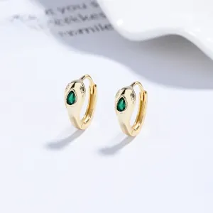 Macro shot of gold snake hoop earrings with emerald green zircon and fine diamond accents