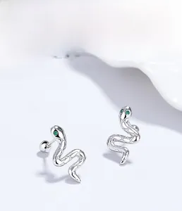 Macro shot of 925 sterling silver snake stud earrings with detailed scales and green gem eyes