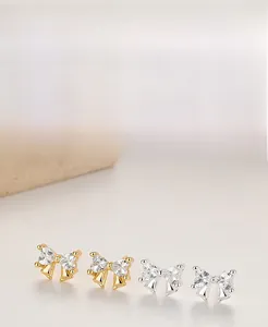 Macro detail of S925 silver bow earrings with heart-cut cubic zirconia in gold and silver