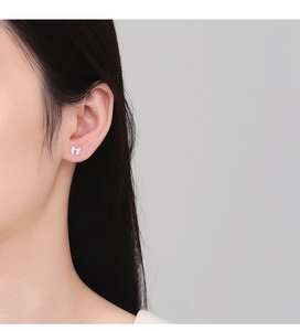 Macro detail of silver bow stud earrings with sparkling cubic zirconia on a model