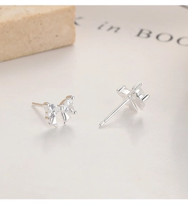 Macro detail of 925 silver bow stud earrings featuring heart-shaped zirconia stones