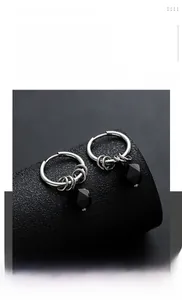 Macro shot of silver titanium hoop earrings with faceted black zircon dangles for men
