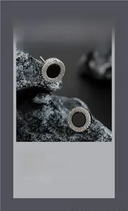 Macro shot of silver stud earrings with caviar texture and black circular inlay details
