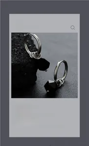 Detailed macro shot of minimalist silver hoop earrings with black geometric beads and rings