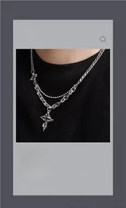 Close-up of gothic cross pendant with layered silver chains for a punk streetwear look