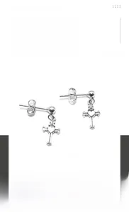 Detailed close-up of hip-hop cross earrings with heart relief in silver titanium steel