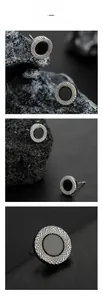 Macro detail of silver-tone circular earrings with textured edges and black inlay