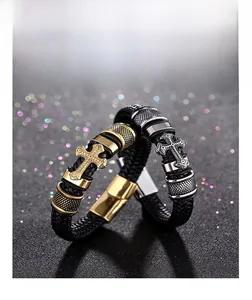 Detailed view of woven leather bracelets with silver and gold engraved cross charms
