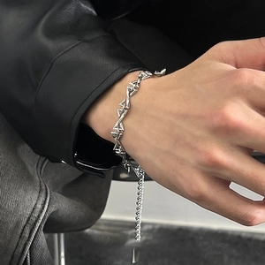 Hip-hop silver metal bracelet with triangular interlocking links on a leather jacket cuff