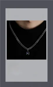 Macro detail of silver cuban link chain with a square deep blue gemstone pendant