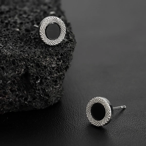 Minimalist silver stud earrings with black inlay on industrial stone and leather base