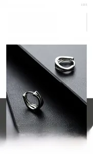Close-up of polished silver titanium steel huggie earrings with geometric layered design