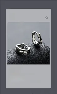 Close-up of polished silver earring with geometric facets on a black leather display