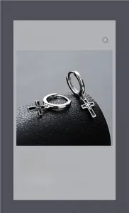 Detailed view of silver cross earring with black enamel fill on a matte stand