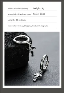 Detail view of 9g stainless steel cross pendant earrings on black volcanic rock background