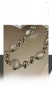 Macro shot of silver beaded necklace with luminous cat eye stones on mirror surface