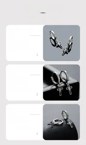 Detail of silver hoop earrings featuring a layered black and silver cross pendant