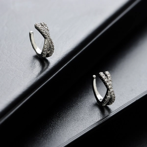Boucles d'oreilles croisées argentées avec cristaux micro-pavés sur support noir
