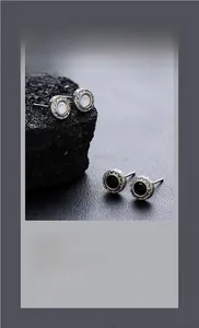 Gros plan de boucles d'oreilles minimalistes avec pierres noires et opales sur roche noire