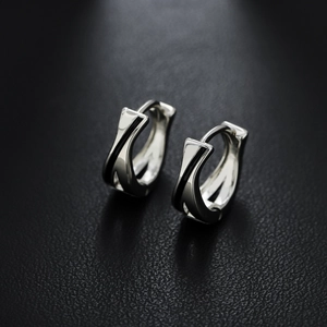 Polished silver geometric hoop earrings with black enamel inlay on black leather background
