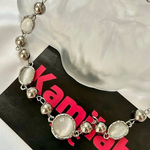 Minimalist moonstone beaded necklace with silver metal beads on a silk fabric background