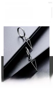 Macro detail of silver titanium steel triangle earrings on black textured leather surface