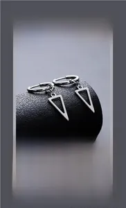 Macro detail of geometric triangle pendant hoop earrings with polished steel finish