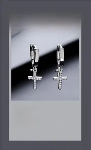 Macro shot of silver hoop earrings with diamond-encrusted double cross pendants