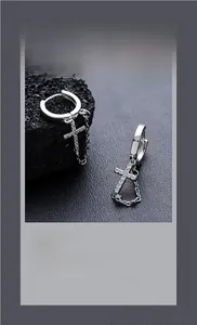Close-up of silver cross earrings with zircon pavé and delicate chain tassel detail