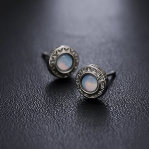 Boucles d'oreilles soleil vintage en argent avec opale sur fond en cuir noir élégant