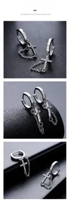 Macro shot of silver cross hoop earrings with inlaid diamonds and delicate chain tassels