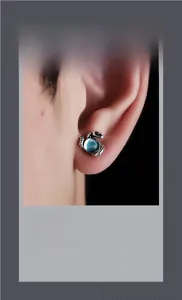 Détail du bijou d'oreille serpent argenté rétro avec une perle turquoise