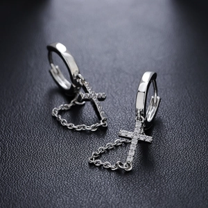 Silver cross earrings with sparkling zircons and delicate chains on a leather background