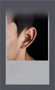 Detail of silver ear cuff with irregular wavy texture on a male ear in a close-up shot