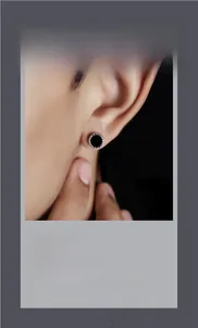 Close-up of a black magnetic clip-on earring with textured silver edges for unisex wear