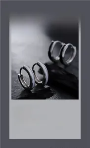 Macro shot of silver hoop earrings with black and white enamel on natural dark stone