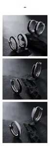 Minimalist silver hoop earrings with black and white enamel inlay on a dark rock surface