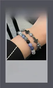 Close-up of beaded bracelets featuring blue marble stones and black beads with cross charms