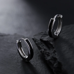 Minimalist silver and black drop glue round hoop earrings on a dark textured rock background
