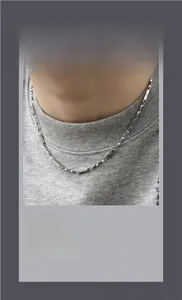 Detail of Mobius chain necklace with star engraved charms in polished stainless steel